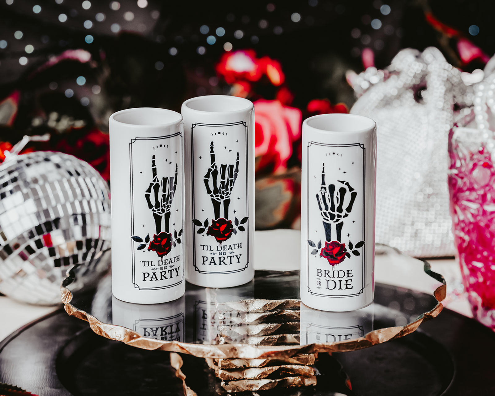 Gothic-style ceramic shot glasses featuring skeleton hand designs with red roses and phrases like "Bride or Die" and "'Til Death Do Us Party," perfect for an alternative bridal party.