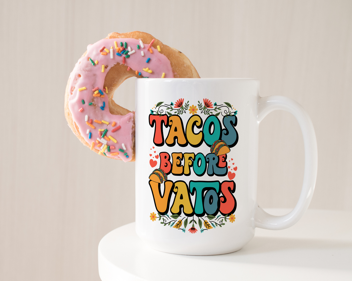 White ceramic mug with bold, colorful “Tacos Before Vatos” text surrounded by floral and taco graphics
